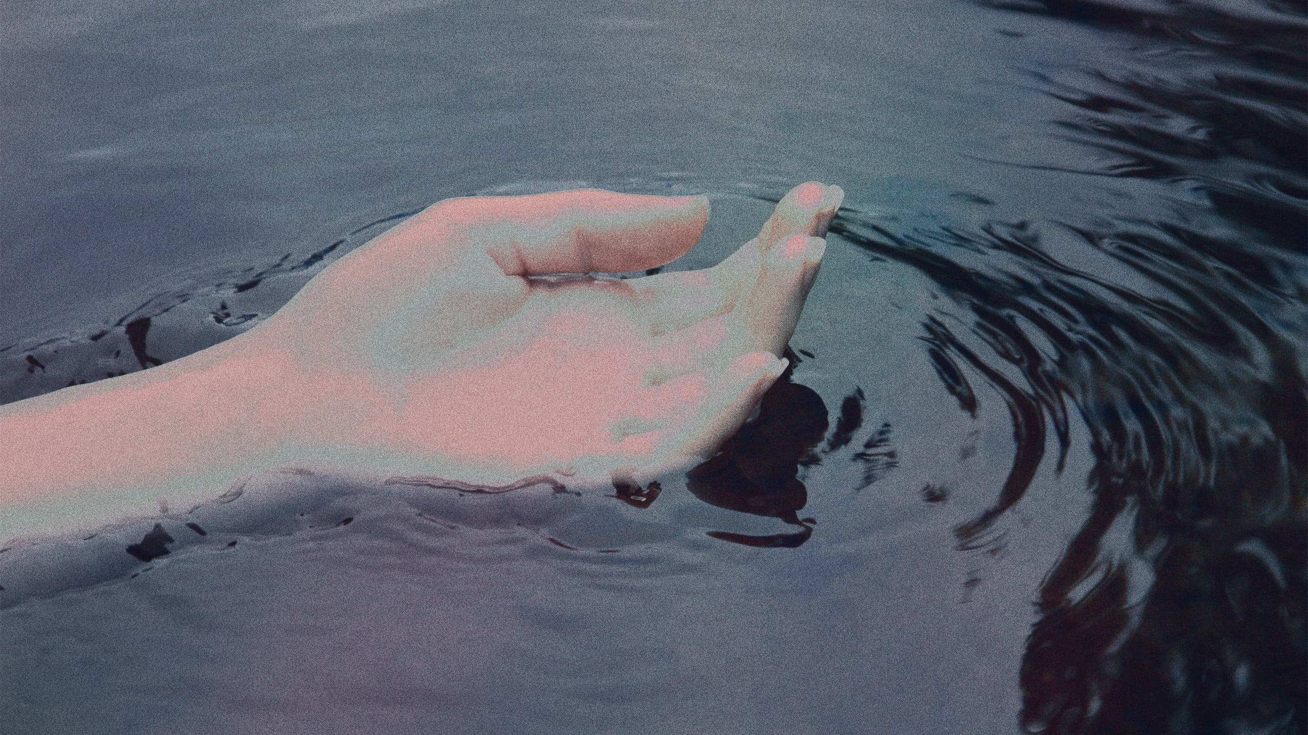#A serene image of a hand gently touching the water, creating ripples, symbolizing calmness and connection with nature